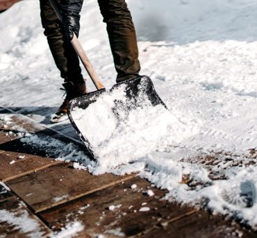 Close up details of working man cleaning out snow from house alley or path using snow shovel